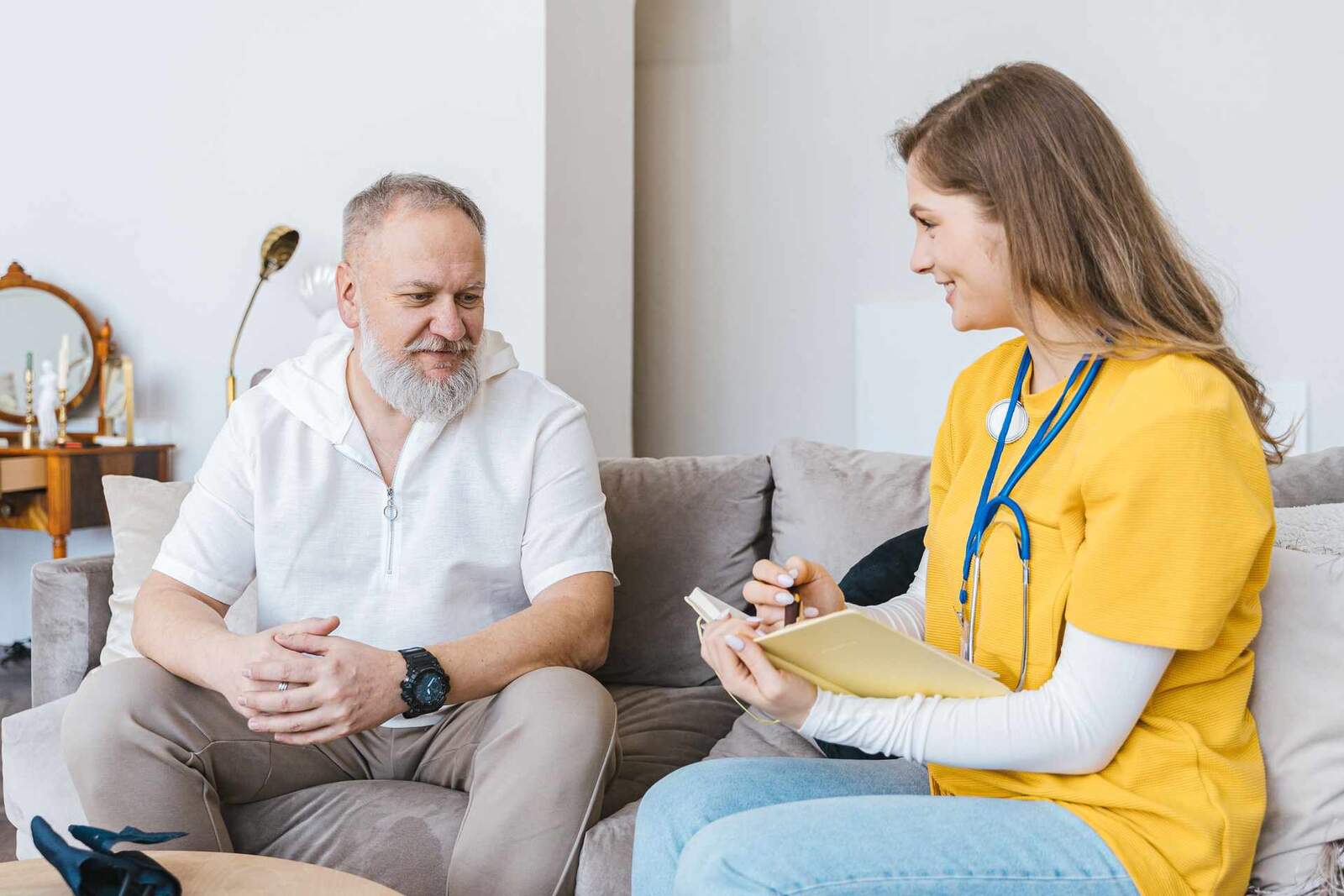 A clinician reviews notes with an older patient during a home consultation
