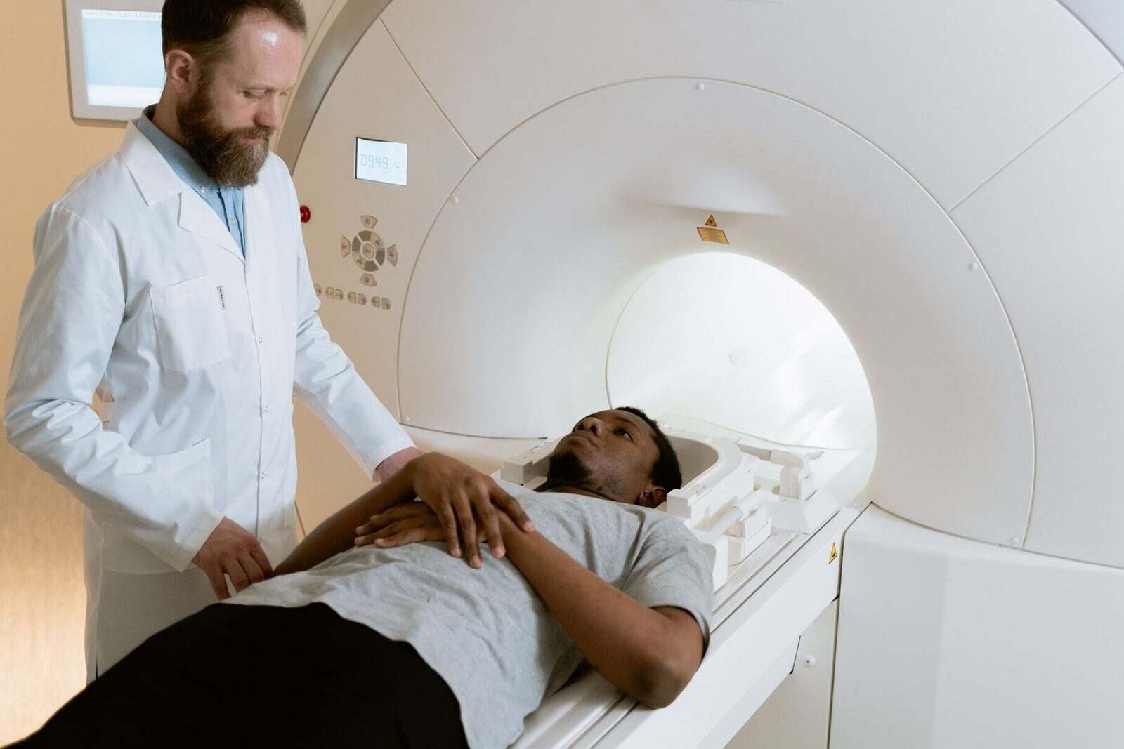 A physician in a white coat positions a patient at the entrance of an MRI scanner