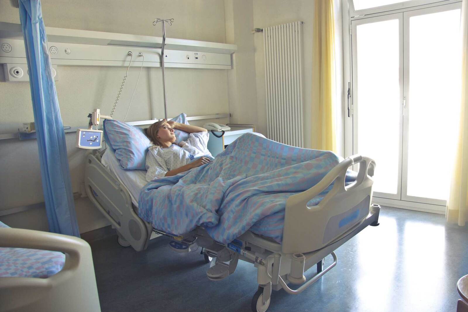 A patient in a hospital bed with an IV pole, a generic stand-in for the hospital infusion-therapy setting affected by the recall