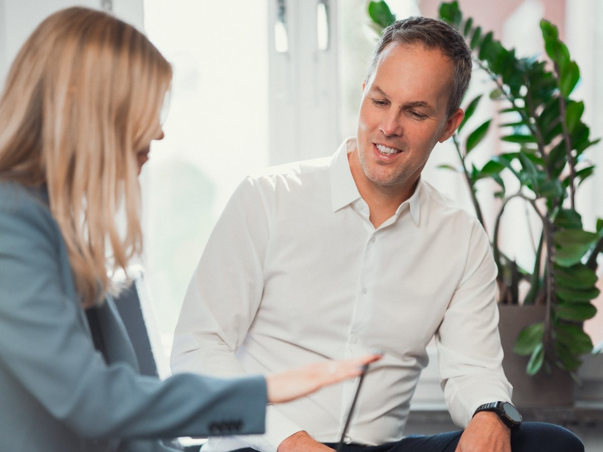 AnaCardio Chief Executive Officer Patrik Strömberg, in a white shirt, talking with a colleague working on a laptop