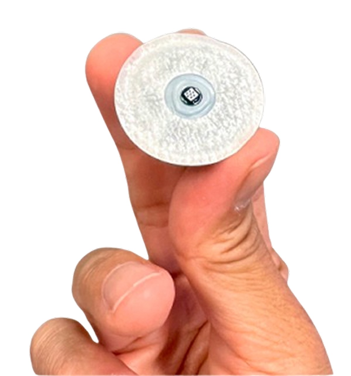 The underside of a Biolinq Shine sensor held between finger and thumb, showing the small square microneedle array at its centre