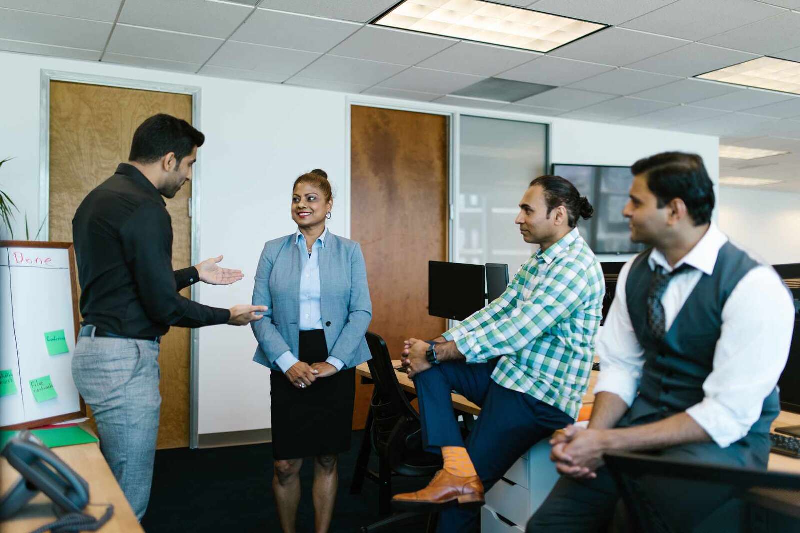 A regulatory team briefing stands around a whiteboard in a bright office