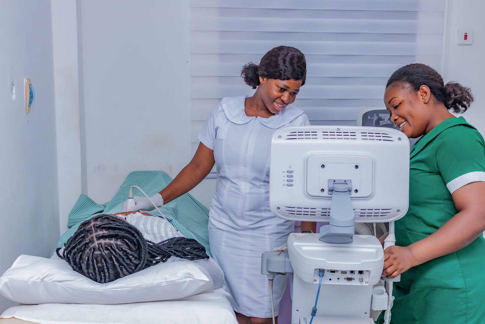 Two clinicians performing a cardiac ultrasound exam on a patient in a bright exam room