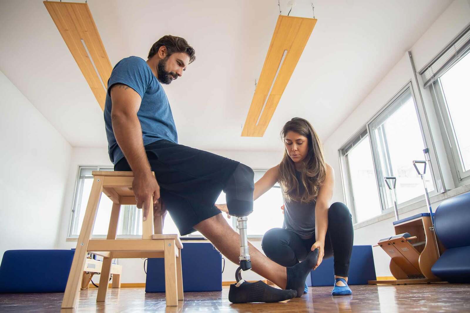 A physiotherapist in a bright studio helps a patient fit and adjust a prosthetic leg, a generic stand-in for orthopedic device care