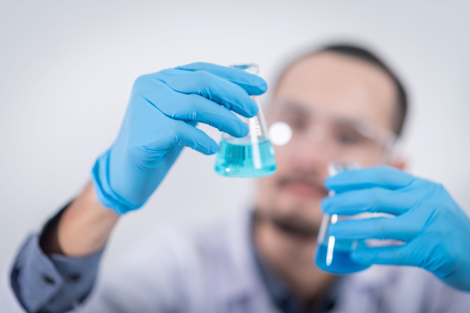 Two researchers in a laboratory examine a blue-tinted flask together