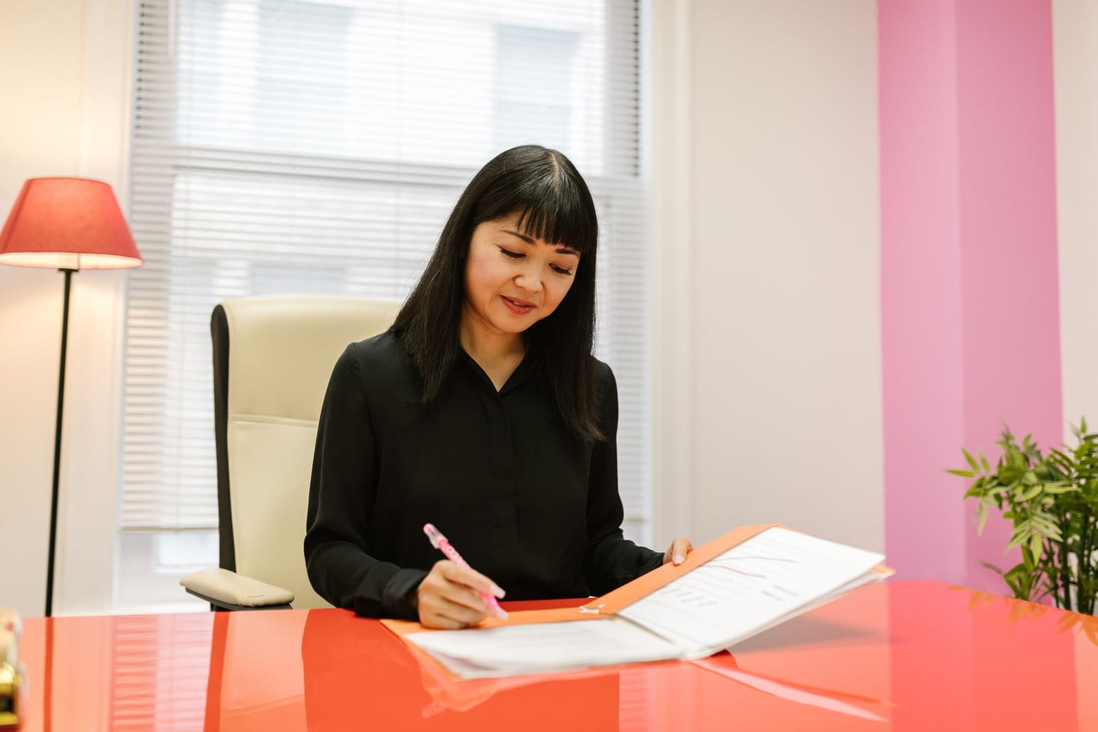 A professional reviews paperwork from an orange folder at a desk