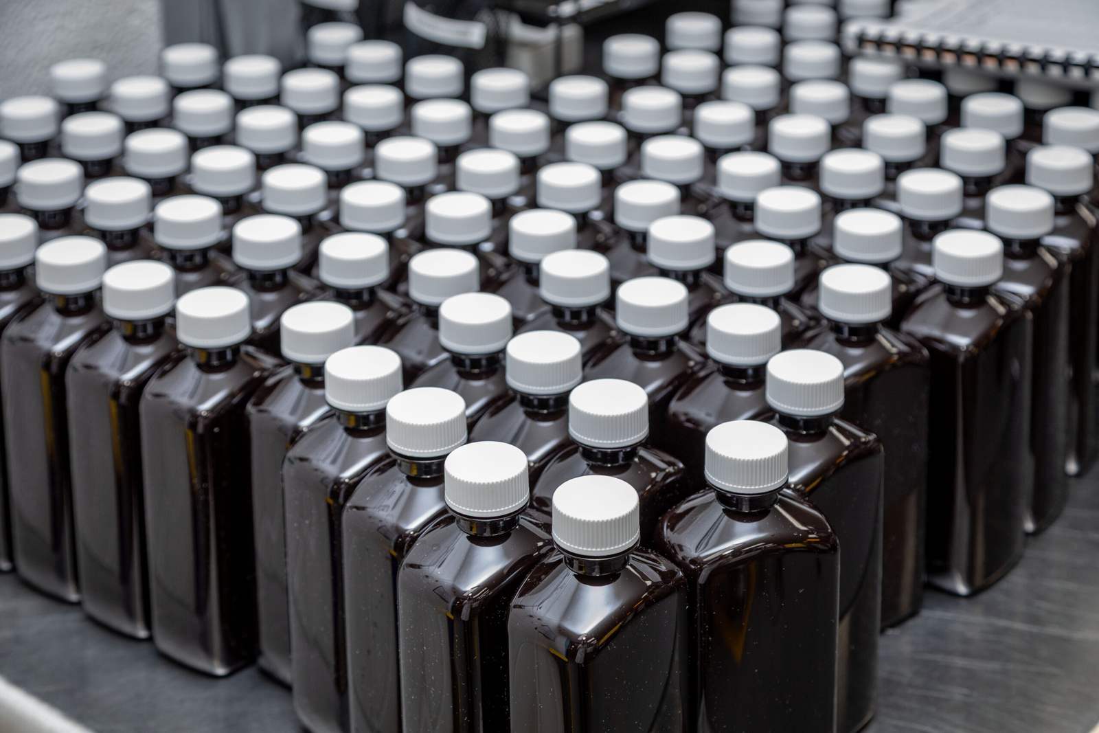Rows of capped amber oral-liquid bottles on a production line at Cosette Pharmaceuticals' manufacturing operation