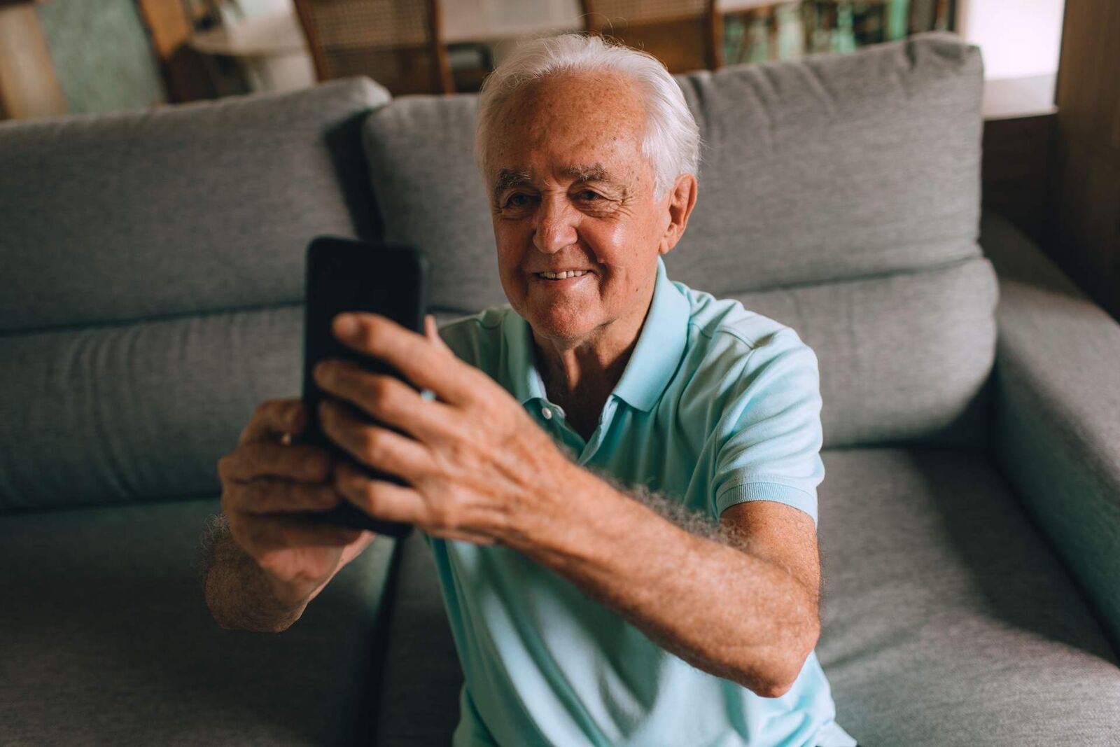 An older adult viewing a smartphone at home, a stand-in for a patient using a prescription drug's companion software