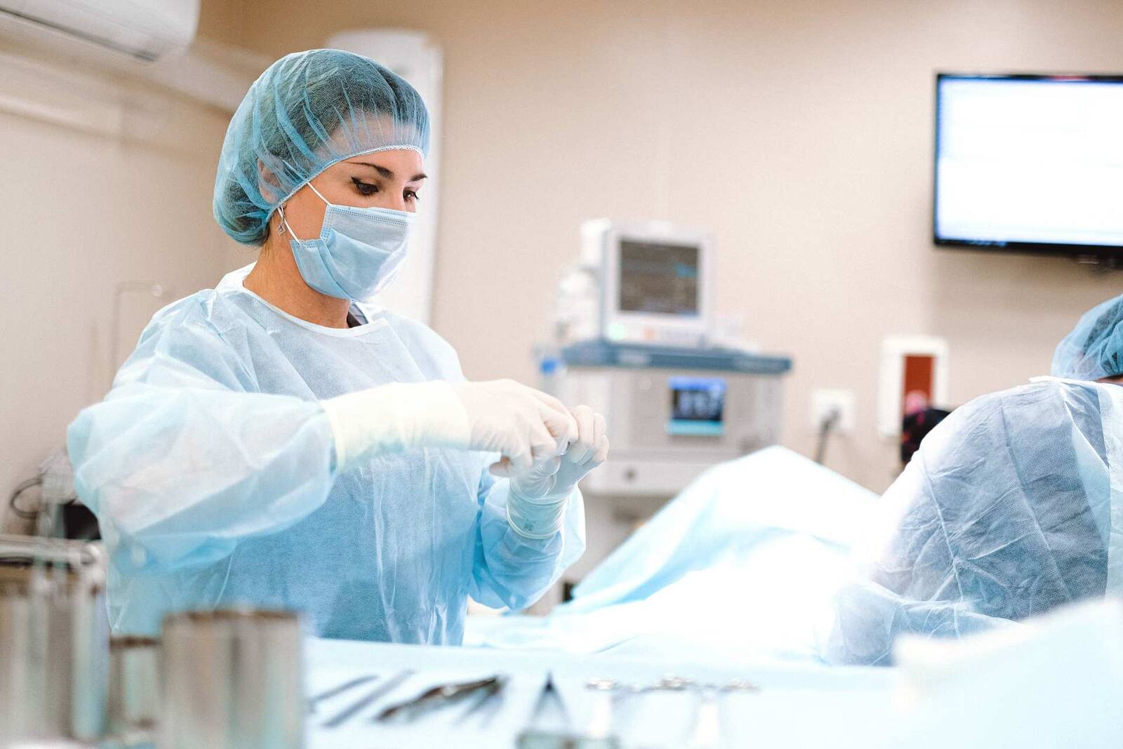 A surgical team member gloving up in a bright operating room, a generic stand-in for a structural-heart procedural setting