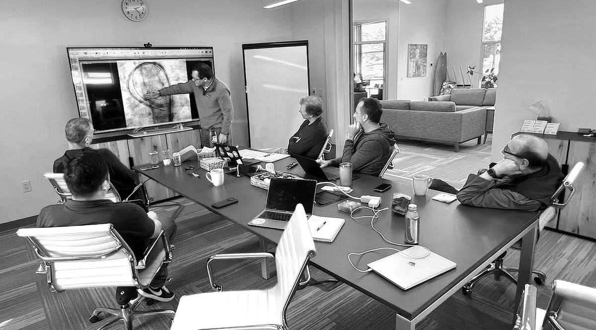 The Emboline team seated around a conference table in its Santa Cruz office while a colleague points to a fluoroscopy image of the aortic arch on a wall screen