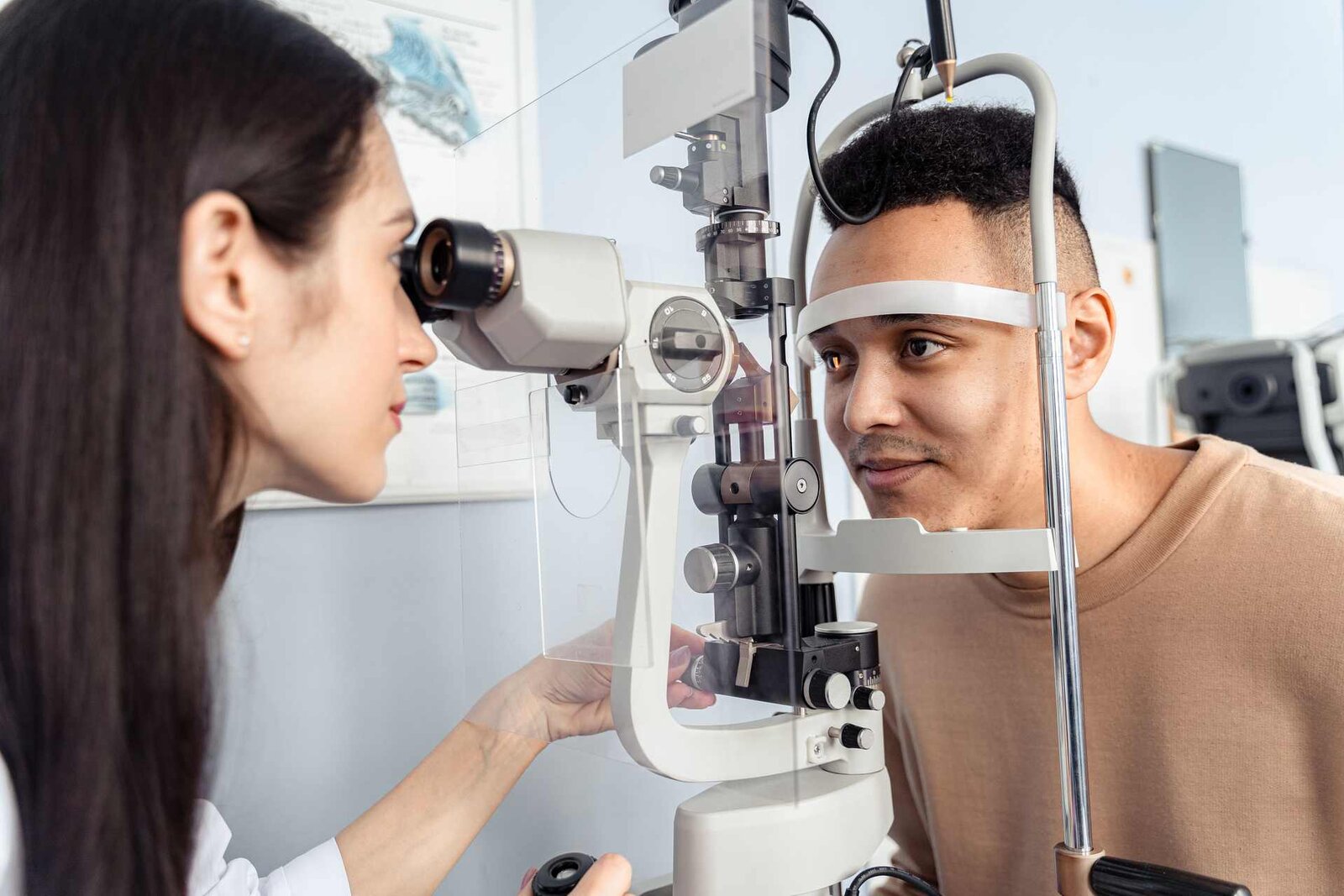 An ophthalmologist examines an adult patient's eye at a slit lamp during a clinic visit