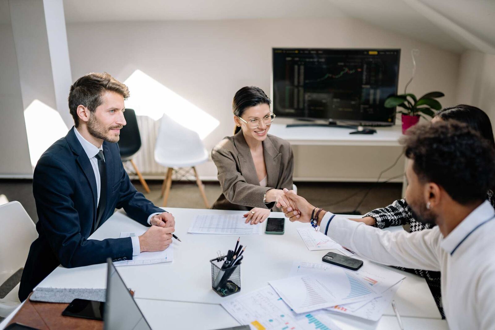 Two colleagues shake hands across a table in a bright office