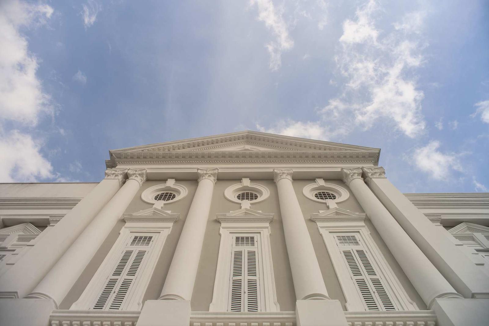 A low-angle view of a neoclassical government building's columns and pediment against a blue sky