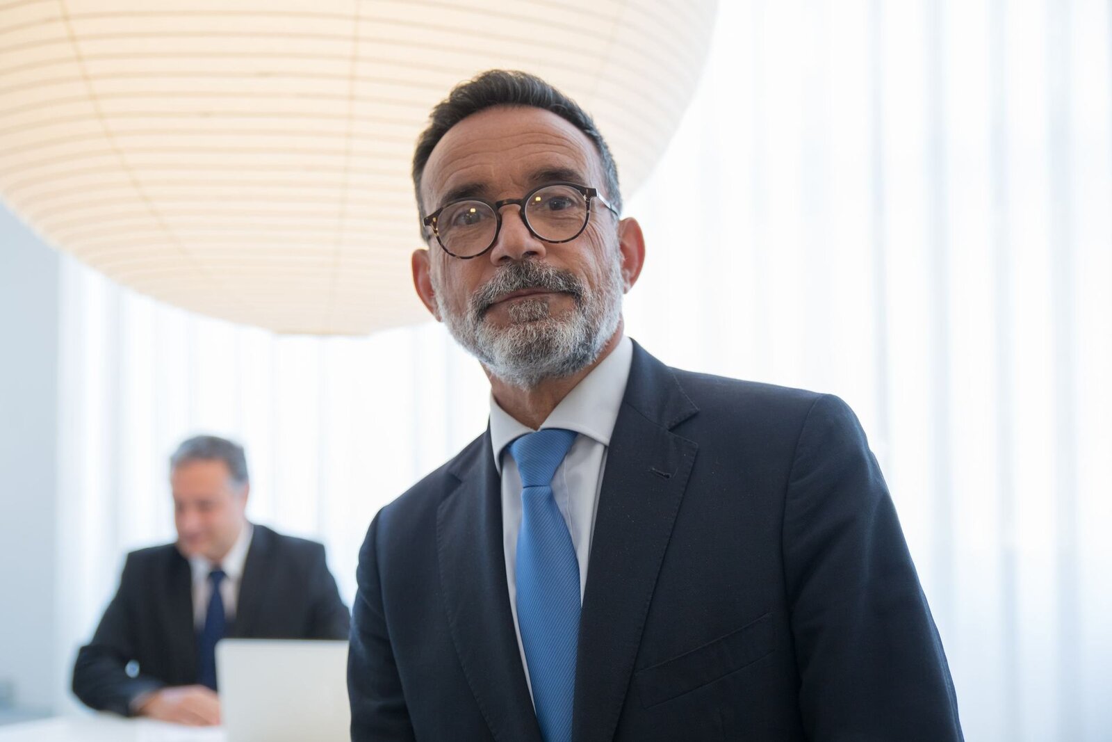 A pharmaceutical executive in an office setting, standing in for the CHMP's review of Eli Lilly's regulatory filing