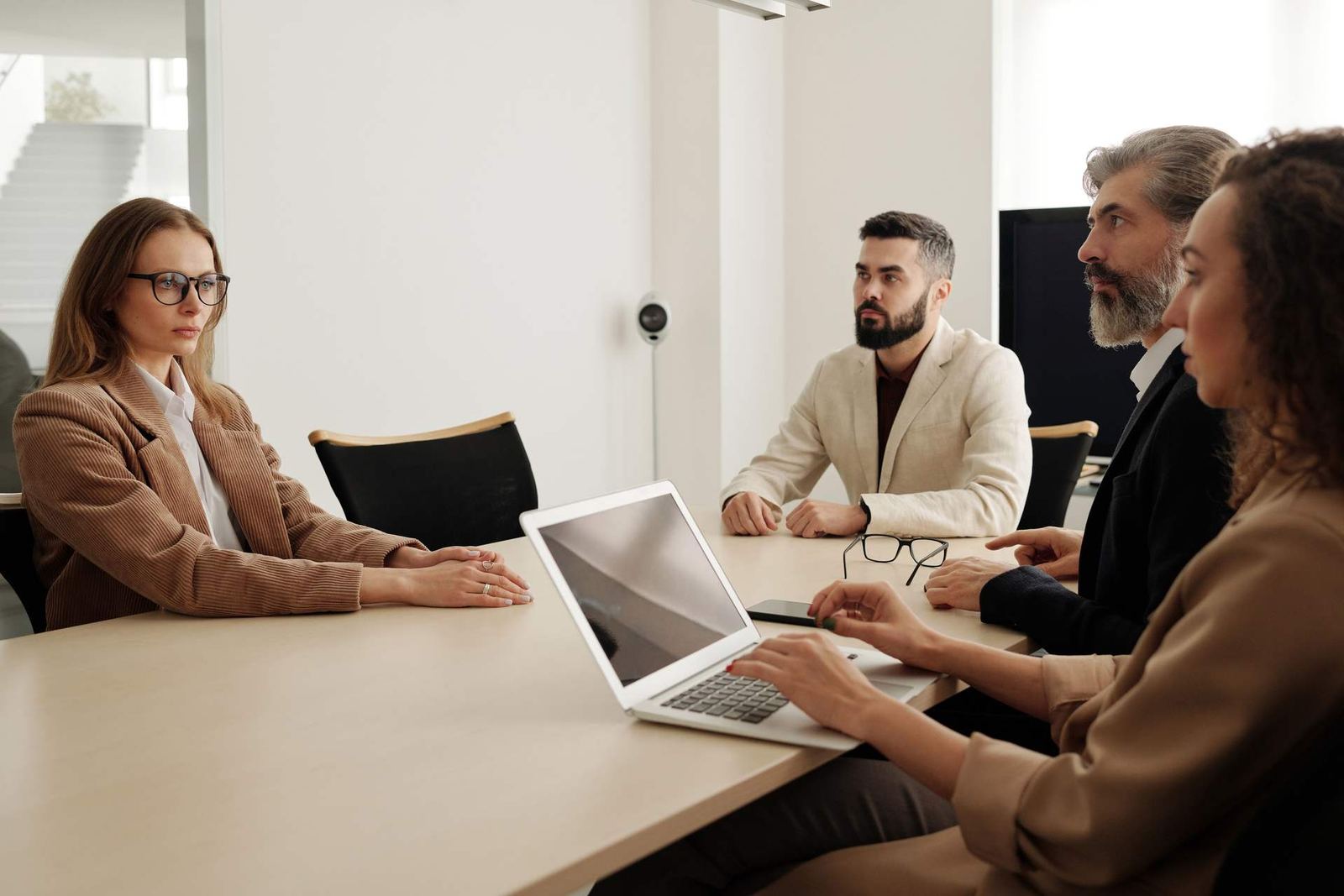 Colleagues around a conference table lean in as one reviews a document, in the middle of a close discussion
