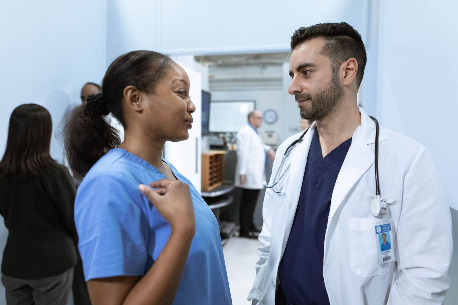 A doctor and nurse confer in a hospital corridor