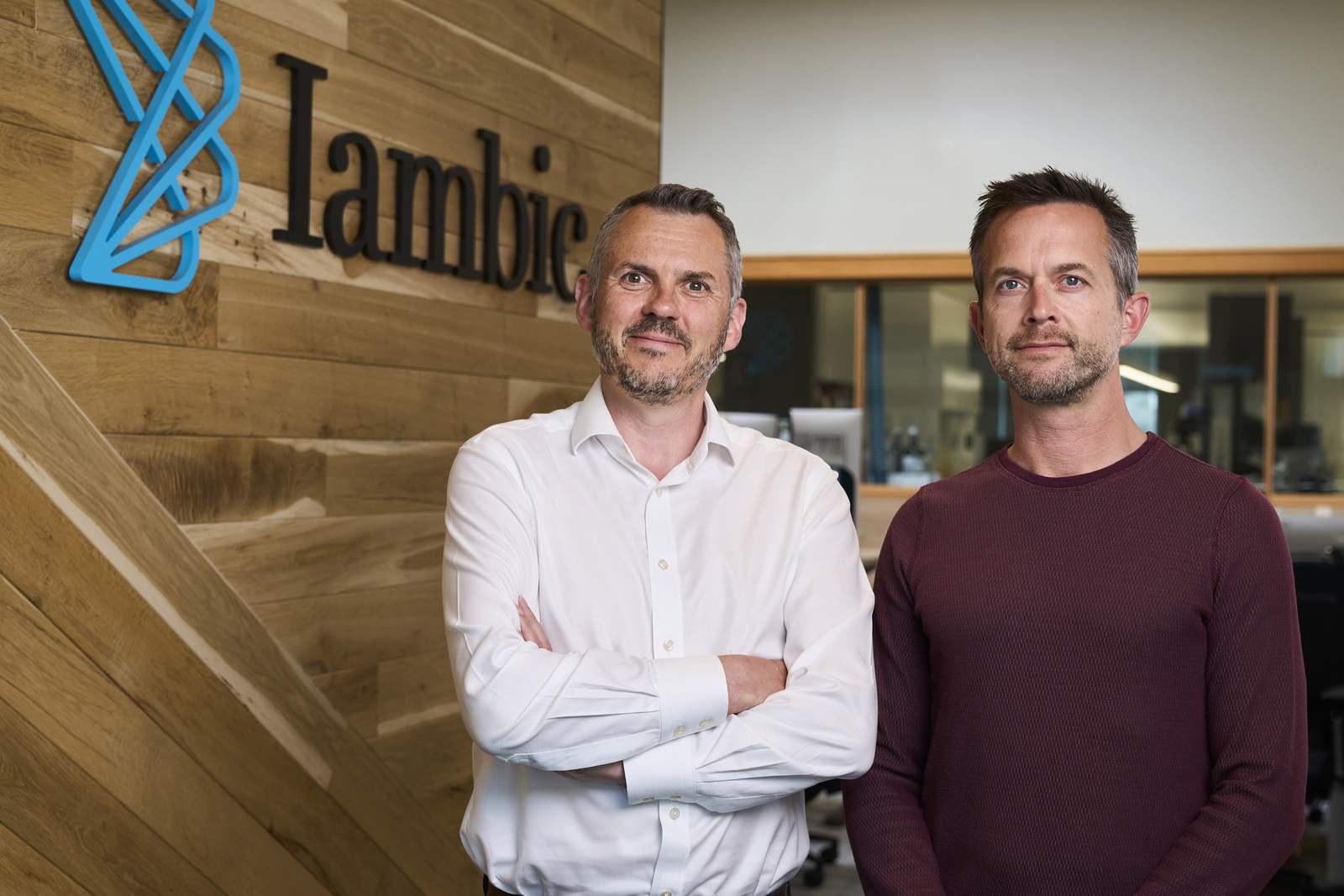 A professional smiles in an outdoor portrait, standing in for the Iambic Therapeutics team marking its Nasdaq debut
