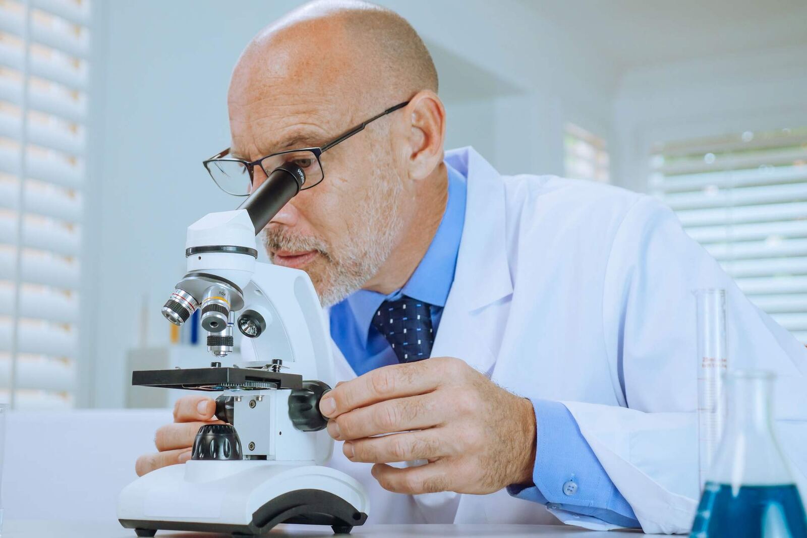 A scientist examines a sample under a microscope in a bright laboratory