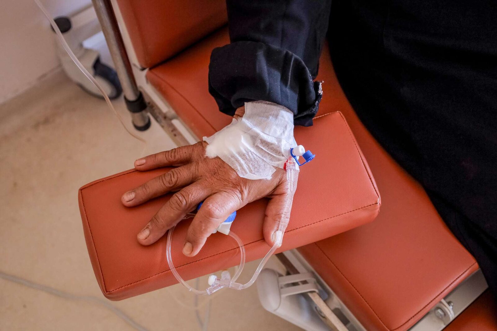 A patient's bandaged hand resting on an infusion-chair armrest, an IV line in place, standing in for Jemperli's intravenous dosing