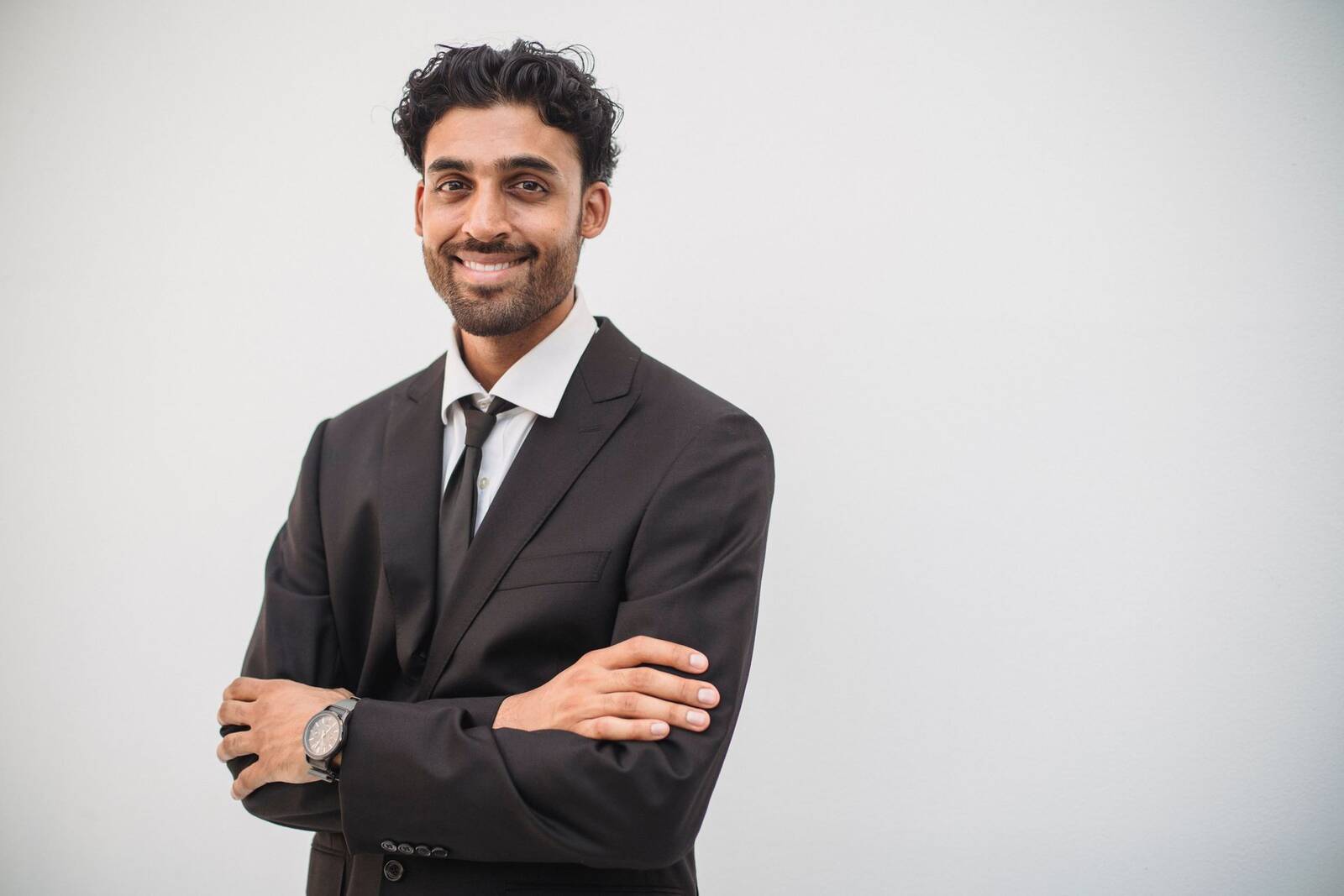 A smiling physician in a dark suit, standing in for GSK's leadership announcing the Jemperli rectal cancer approval