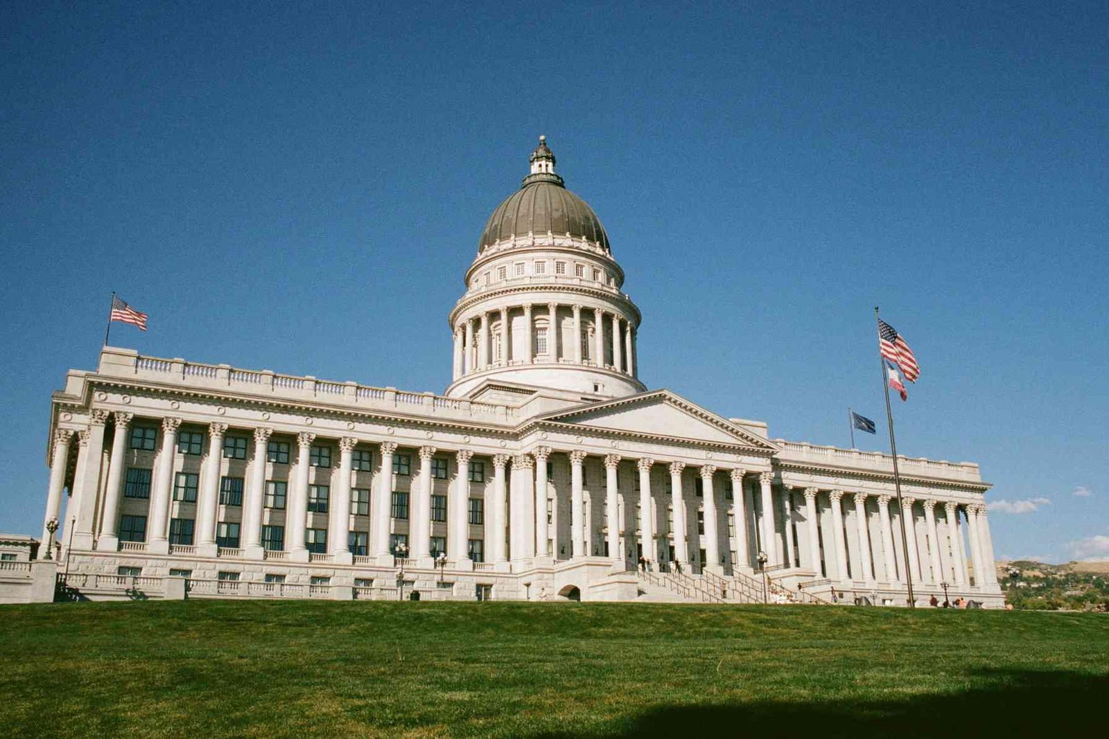 The Utah State Capitol building under a clear blue sky, with American flags flying in front