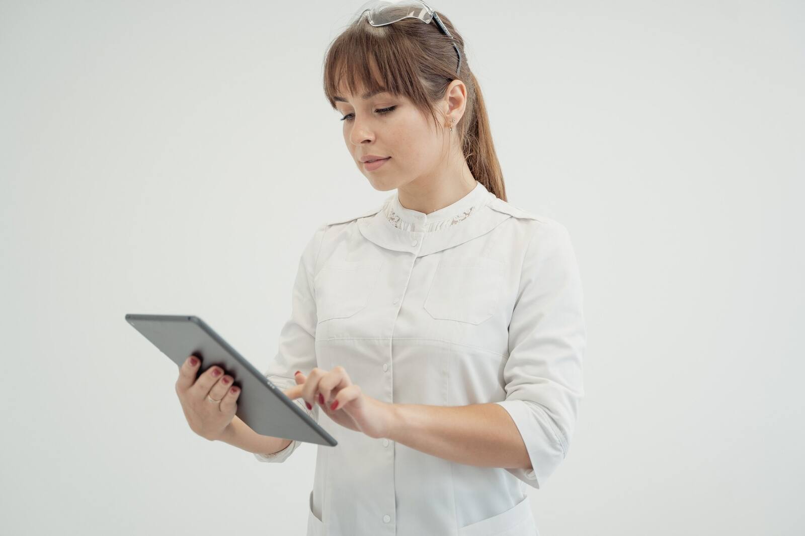 A physician in a white coat reviews information on a tablet