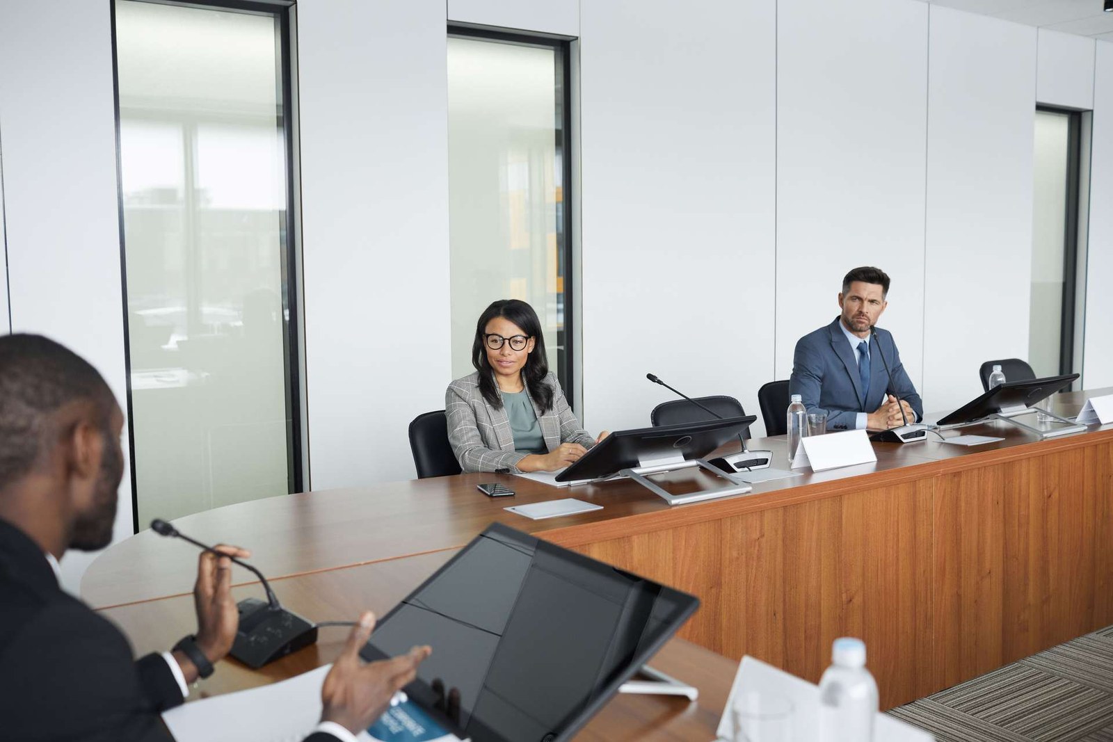 Colleagues seated at a conference table with microphones review documents during a panel discussion