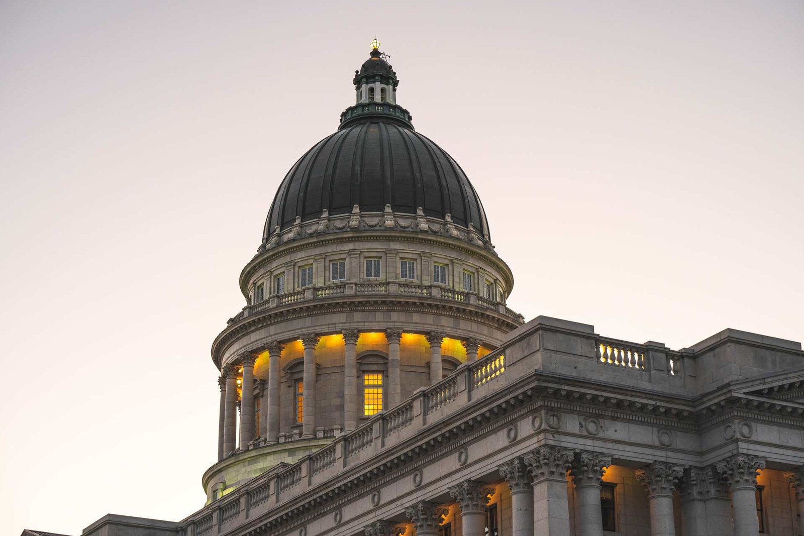 The illuminated dome of the Utah State Capitol building at twilight against a soft pink sky