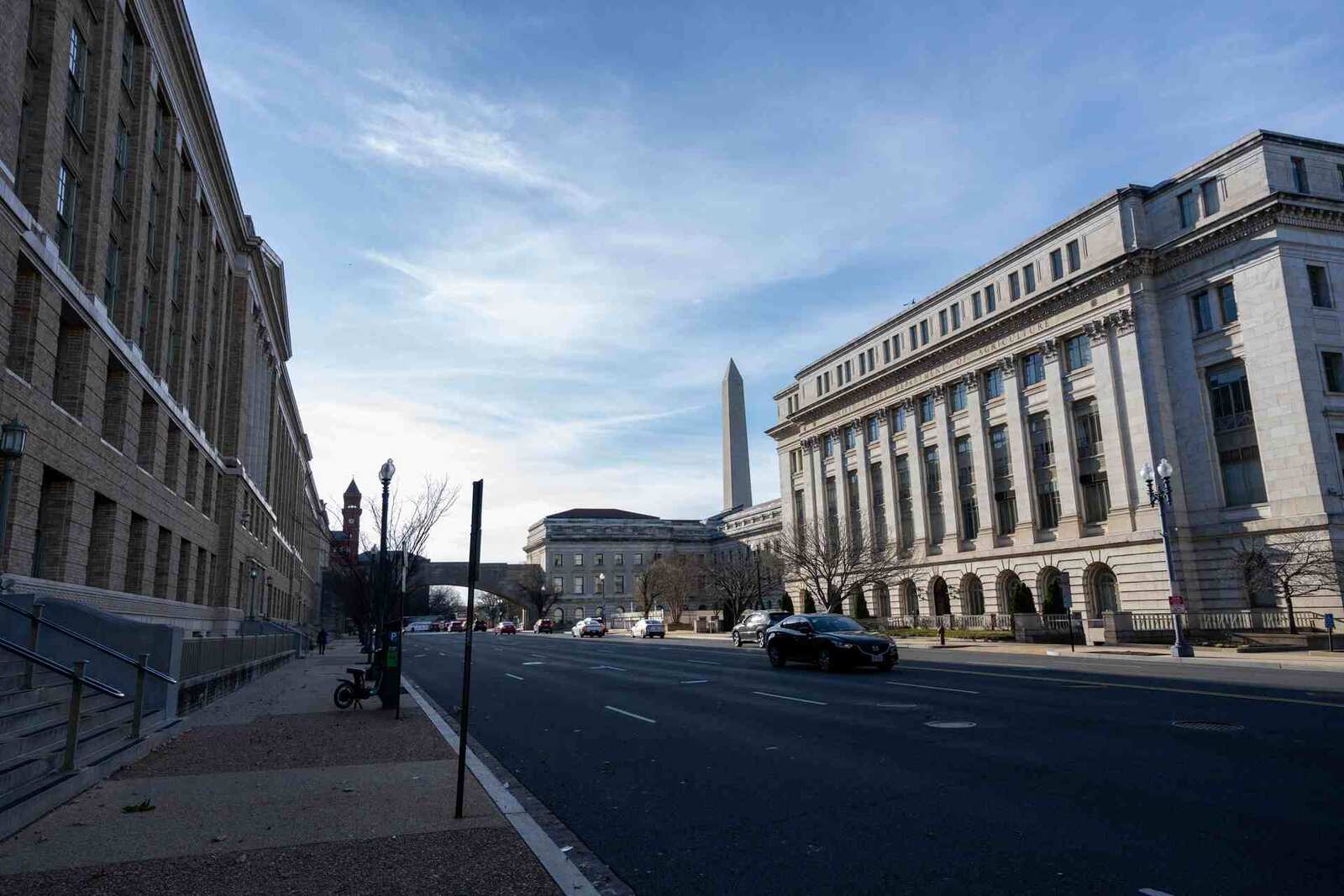 Federal office buildings along a Washington, D.C. street, with the Washington Monument visible in the background