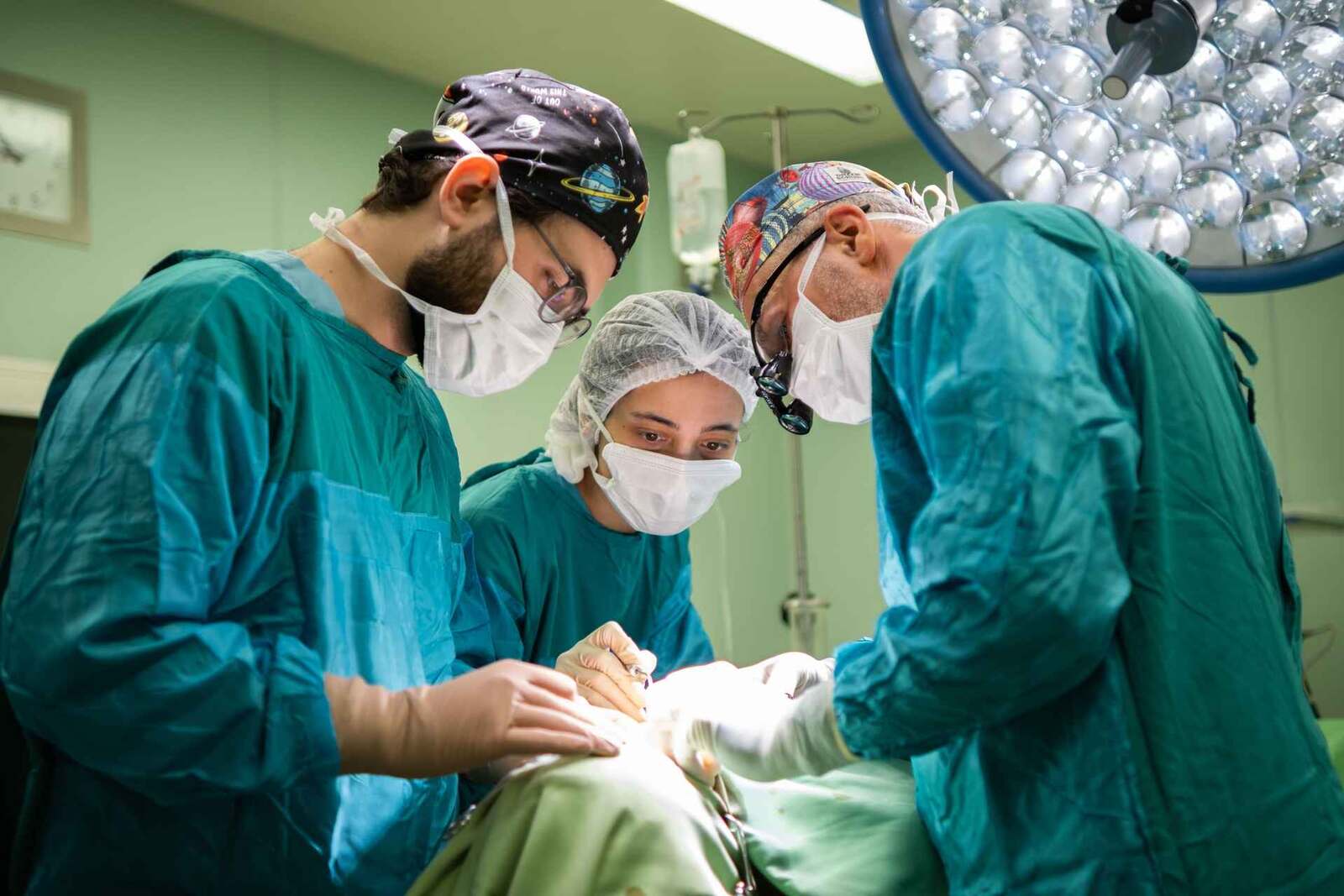 A surgical team works together under bright operating lights during a vascular procedure