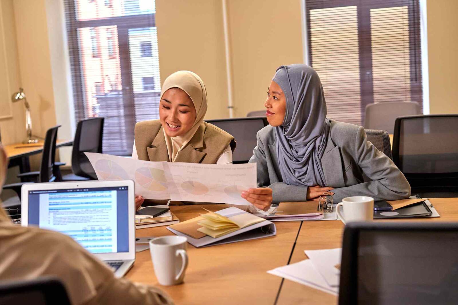 Two colleagues review a printed chart of data together at a conference table