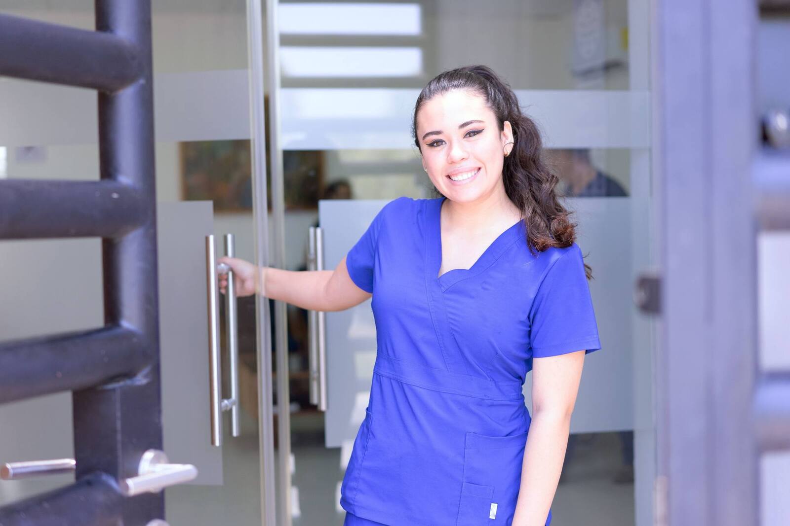A clinician in scrubs at a clinic entrance