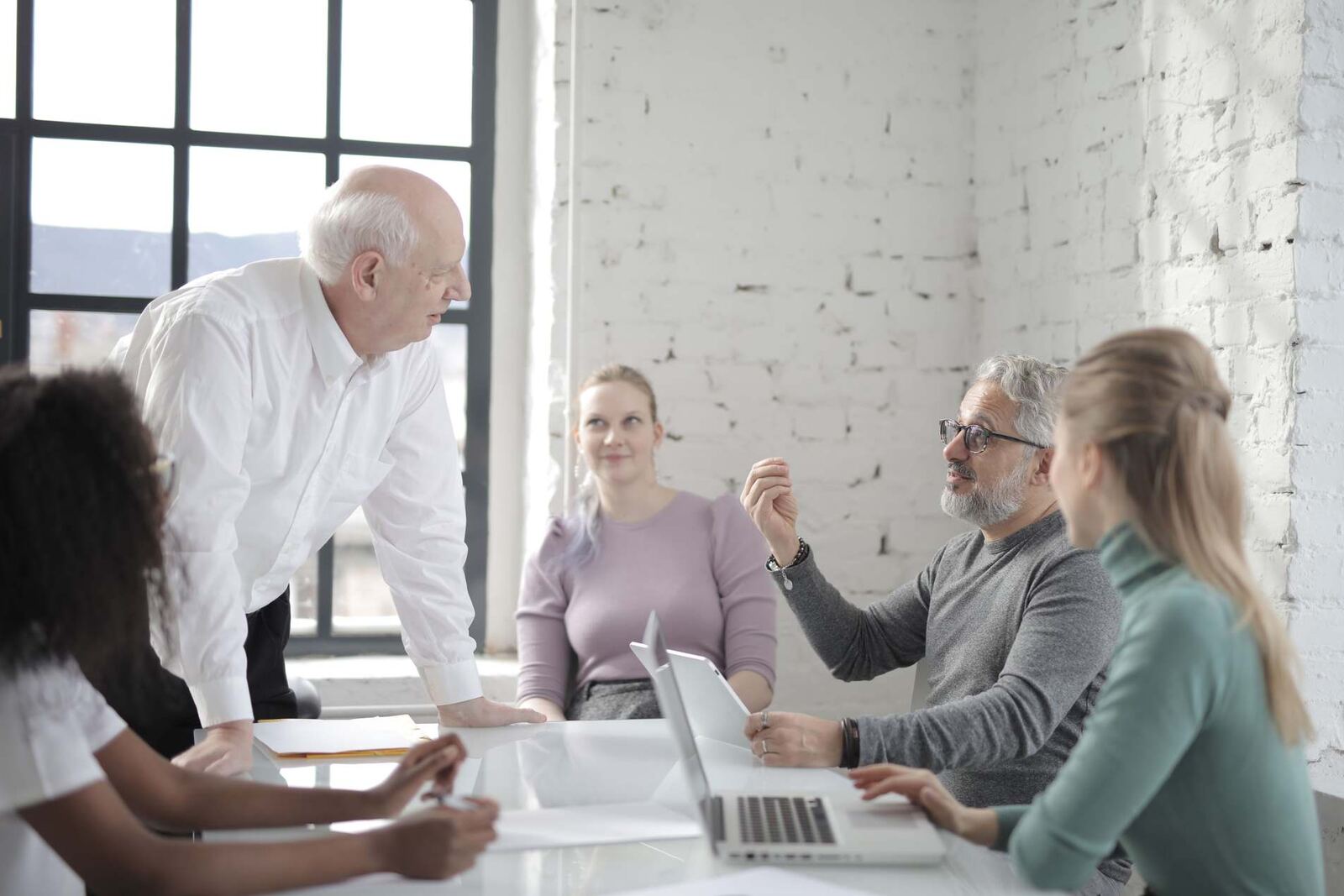 A small team gathers around a table in a bright, modern loft-style office