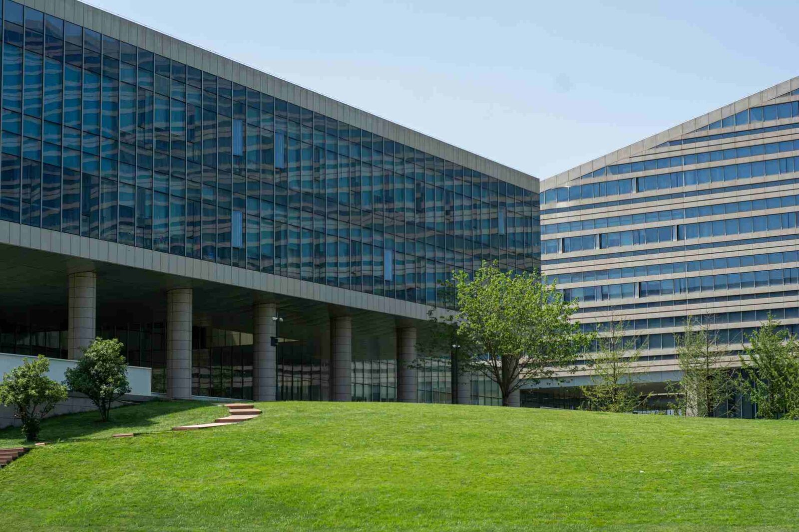 Exterior of a modern glass-and-concrete corporate campus building under a clear blue sky
