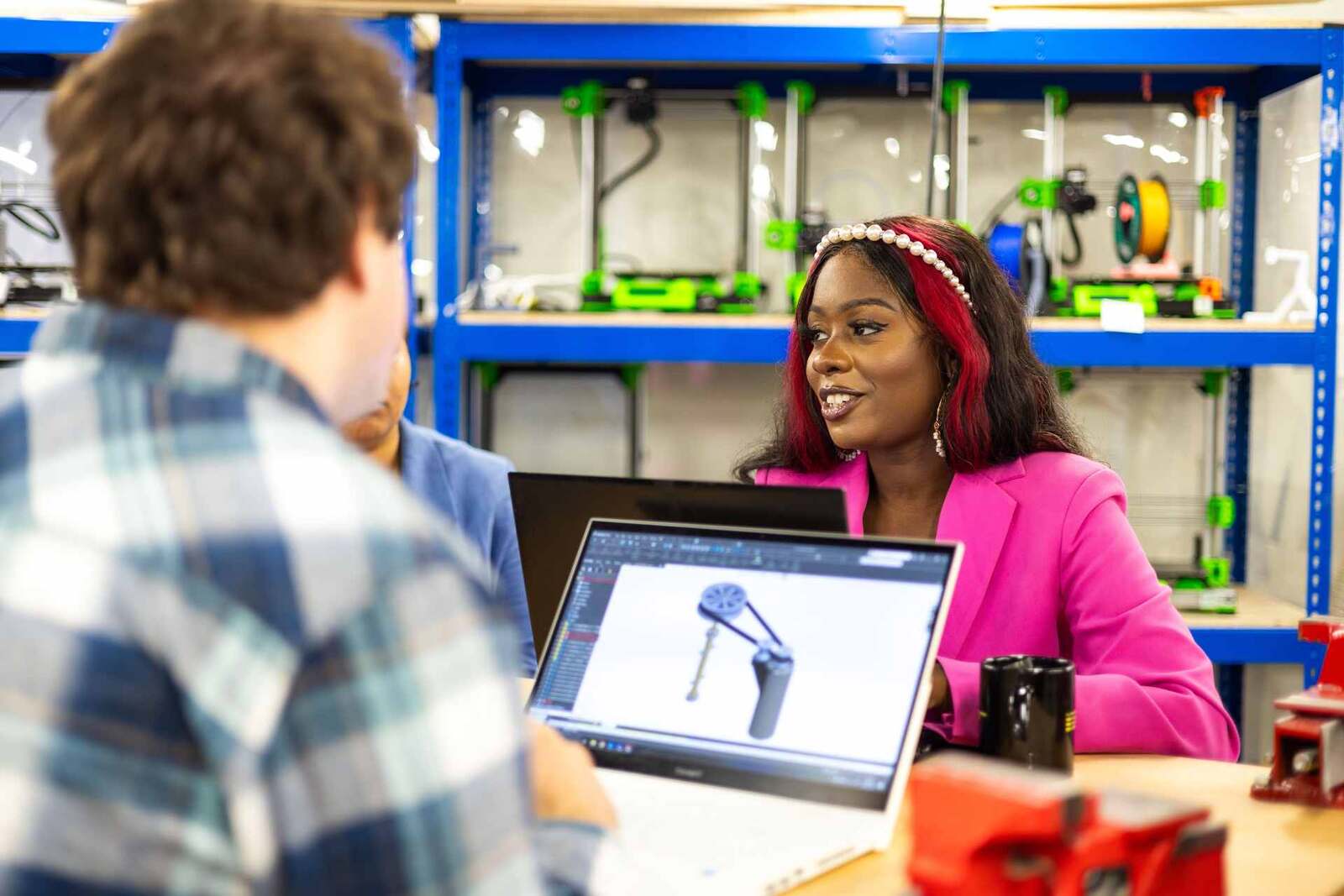 An engineer reviews a 3D product design on a laptop in a prototyping lab