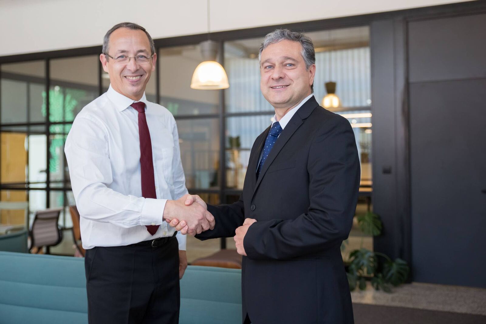 Two colleagues shake hands in a bright office