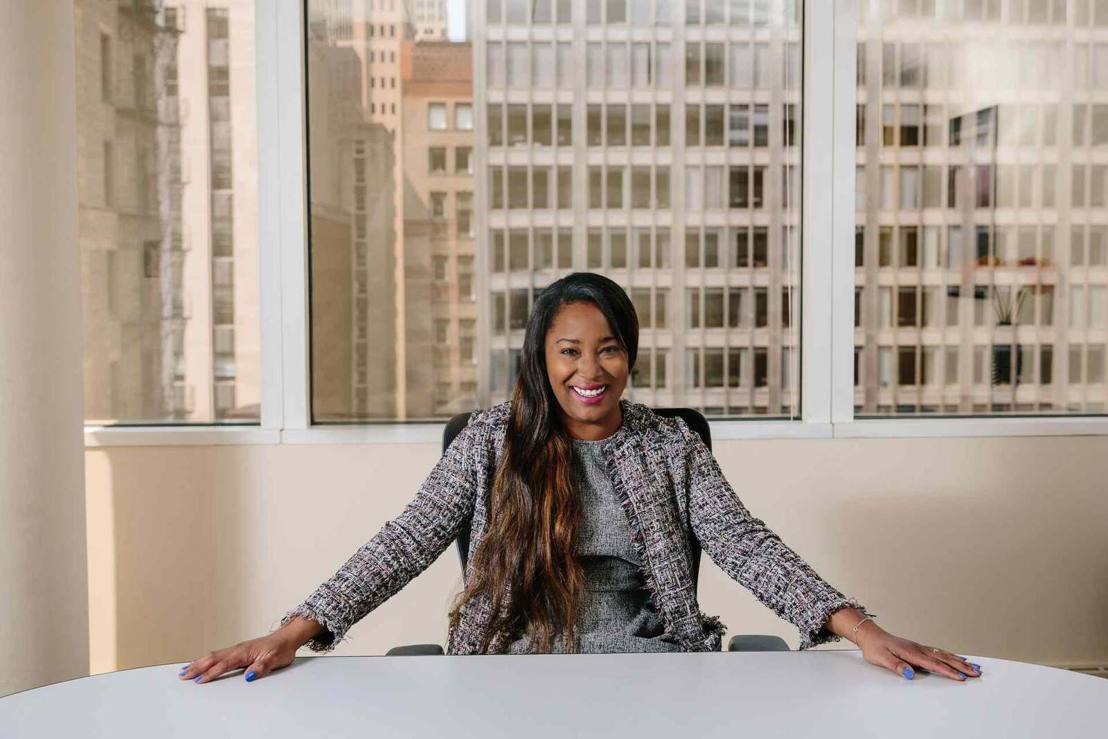 A senior executive smiles at the head of a boardroom table with a city skyline behind, standing in for FDA's cross-center rare disease policy launch