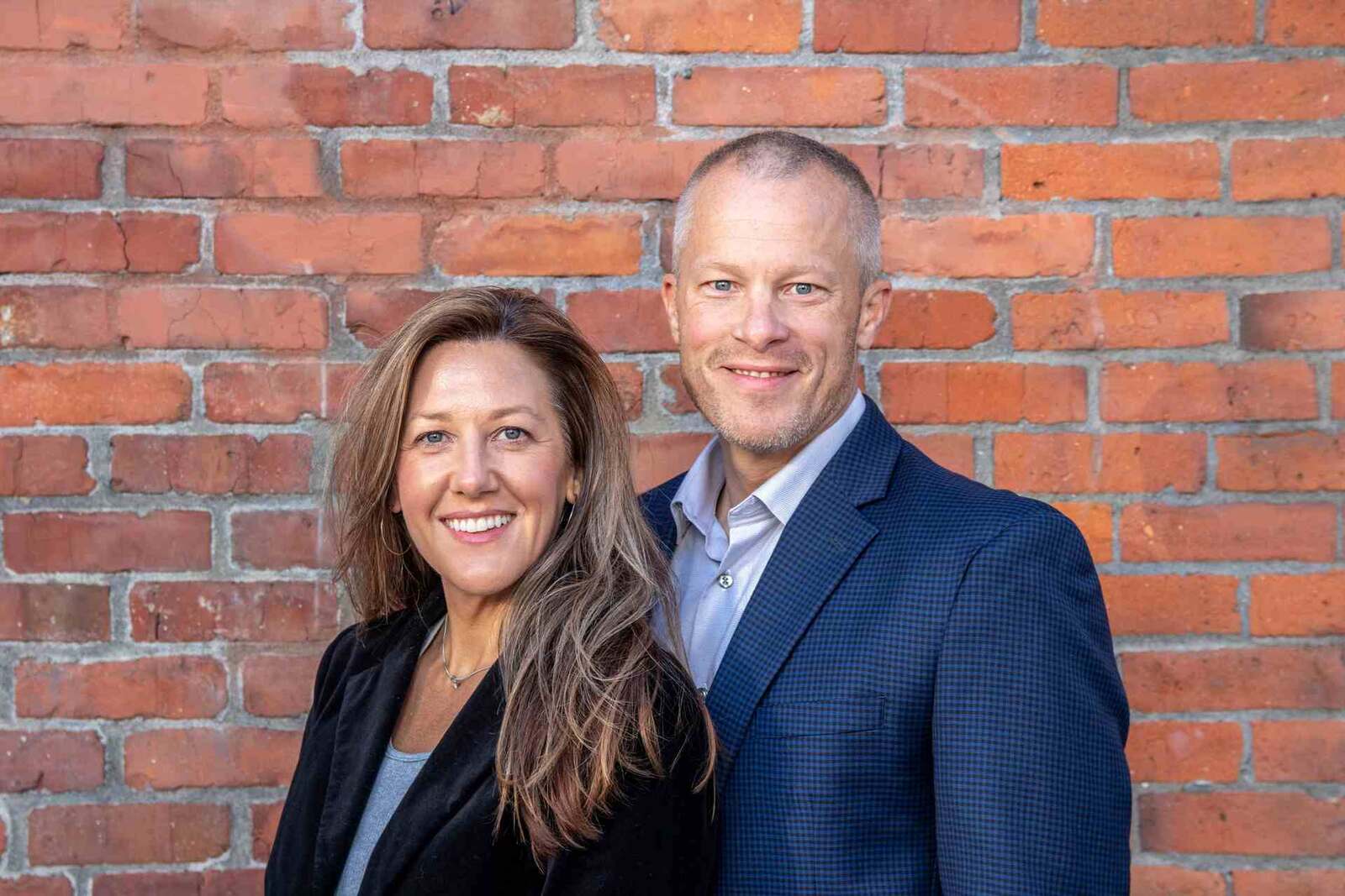 Two business professionals posing together in front of a brick wall, representing Retension Pharmaceuticals' leadership team