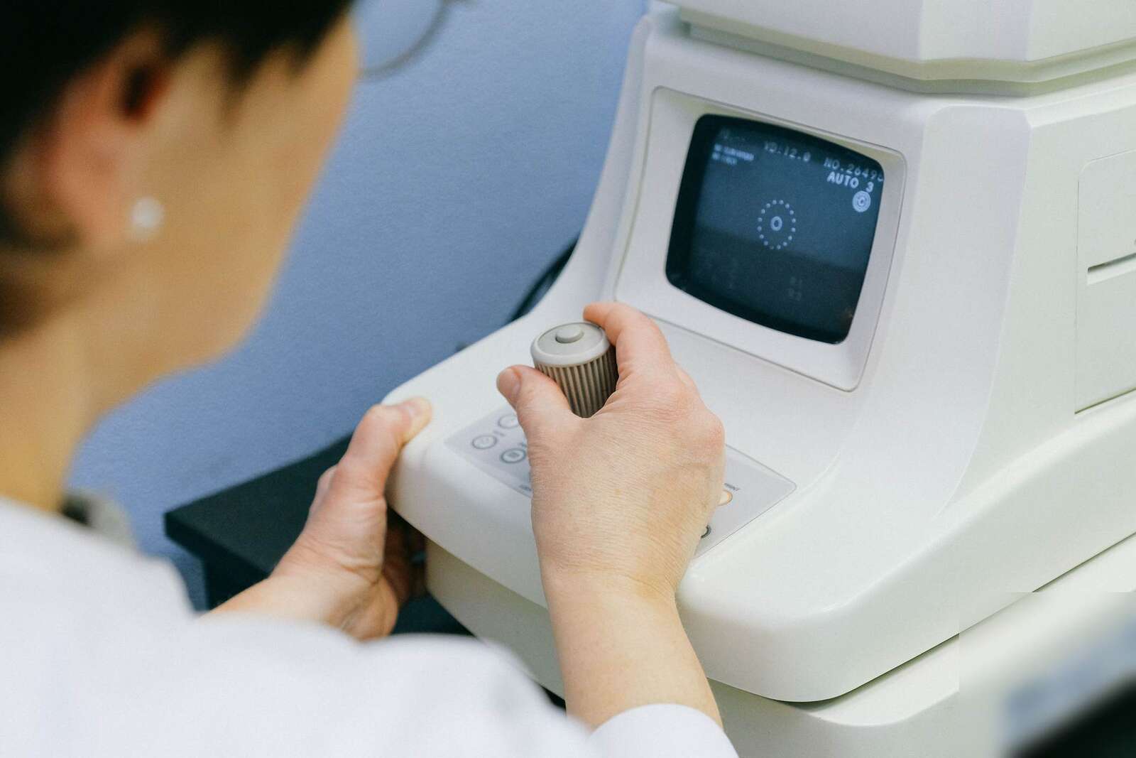 A clinician's hands operate a handheld diagnostic imaging instrument during a patient exam in a clinic, a generic stand-in for ultrasound-guided imaging, not a depiction of RIVANNA's own device or procedure