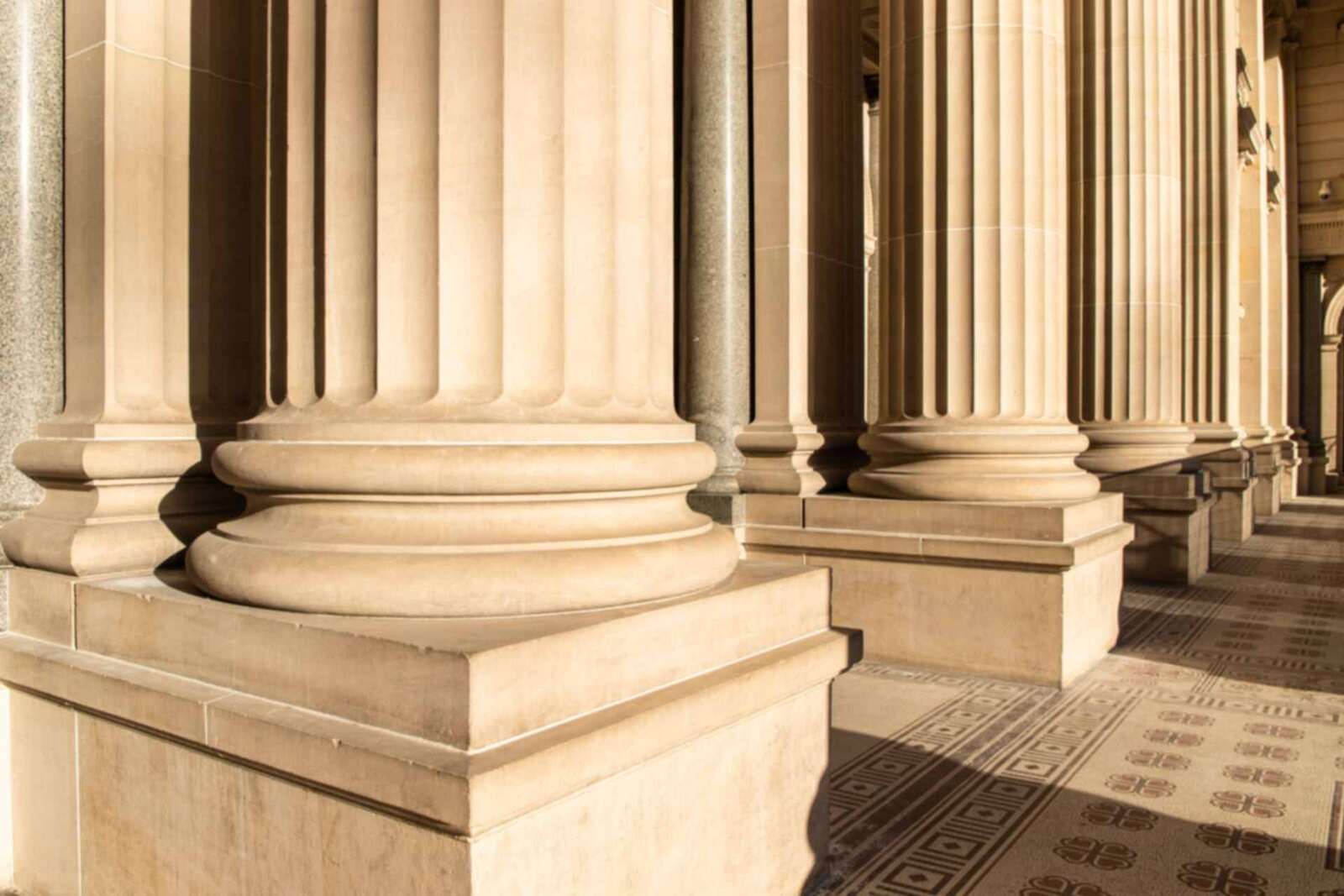 A sunlit stone colonnade with rows of fluted columns, a generic architectural stand-in &mdash; not a depiction of any Roche facility, laboratory or event