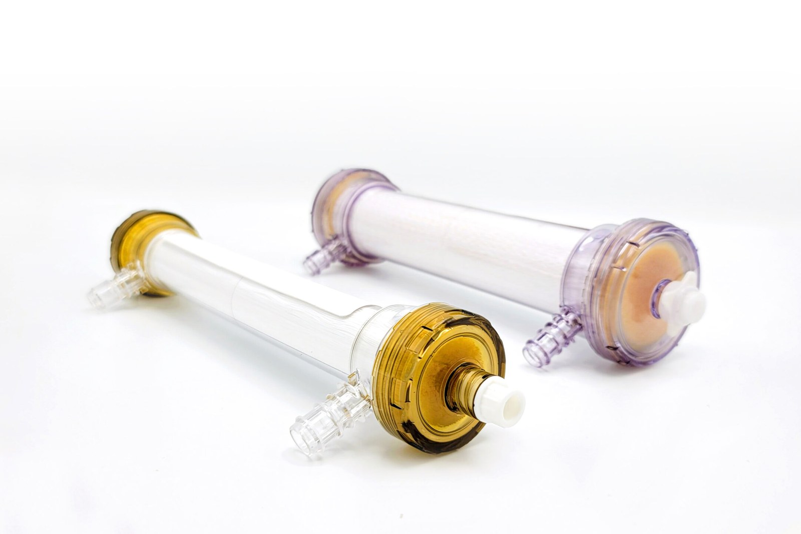Two SeaStar Medical Selective Cytopheretic Device cartridges, the pediatric and adult versions, lying side by side on a white surface, one with amber end caps and one with clear violet end caps