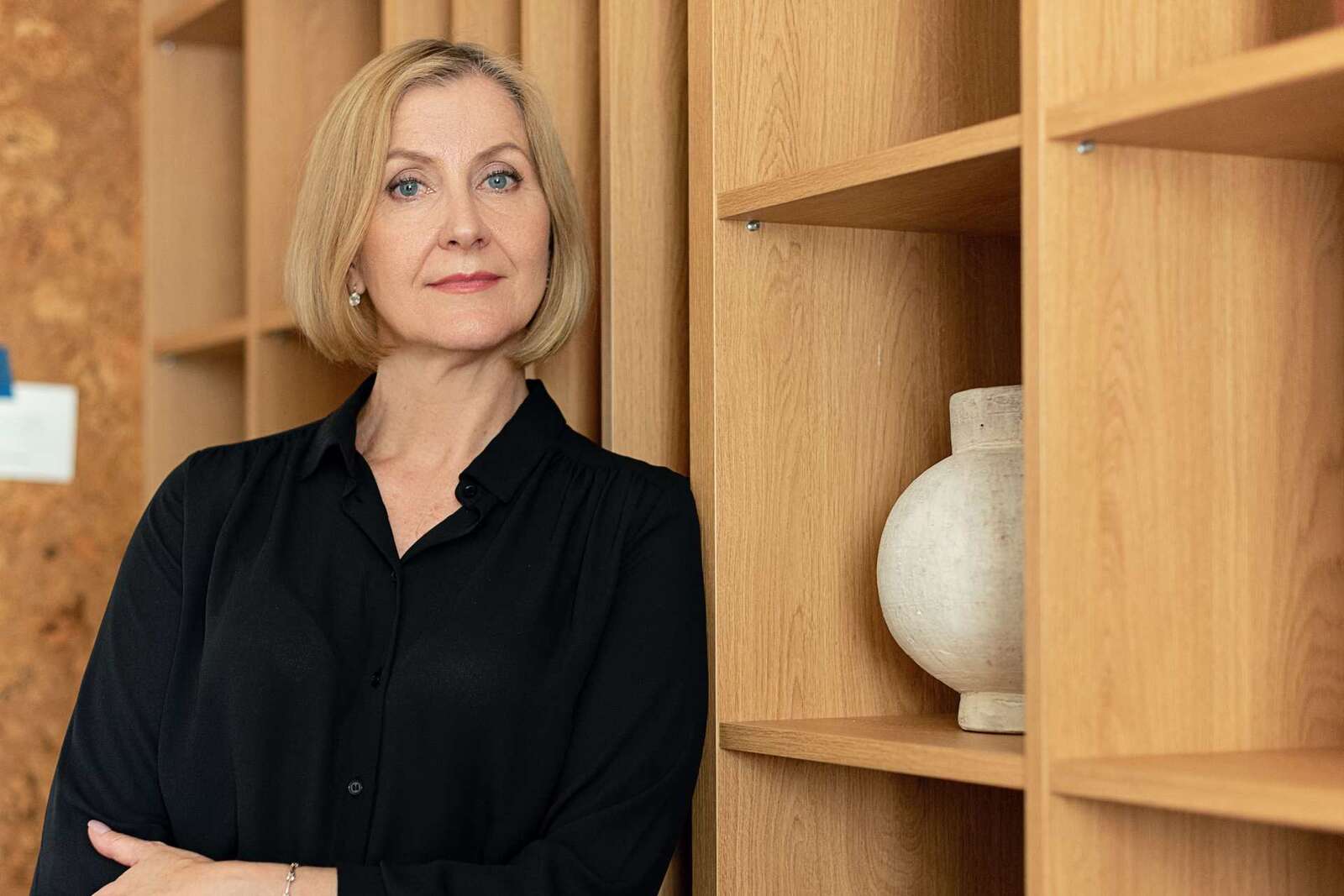 A senior executive in a dark blouse standing by wood shelving, a generic stand-in for AbbVie leadership