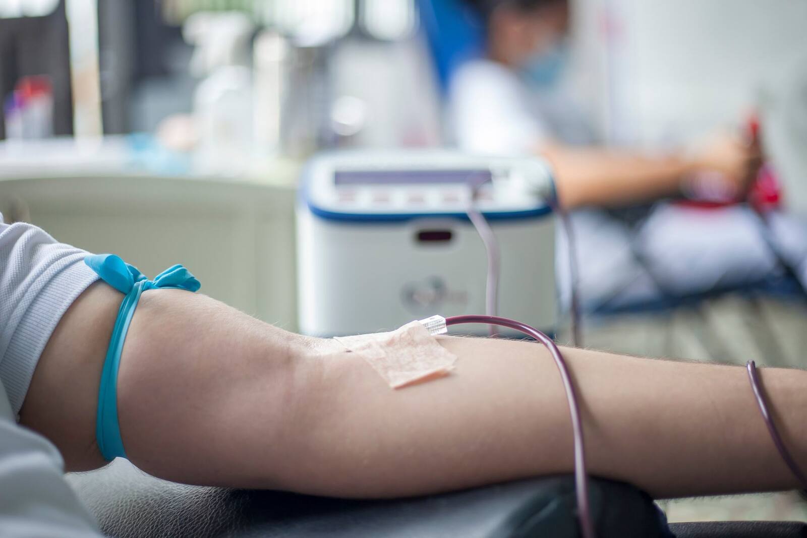 A clinic bedside scene with an IV line taped to a patient's arm and a monitor blurred behind, a generic vascular-access stand-in, not a depiction of a Freesolve RMS procedure