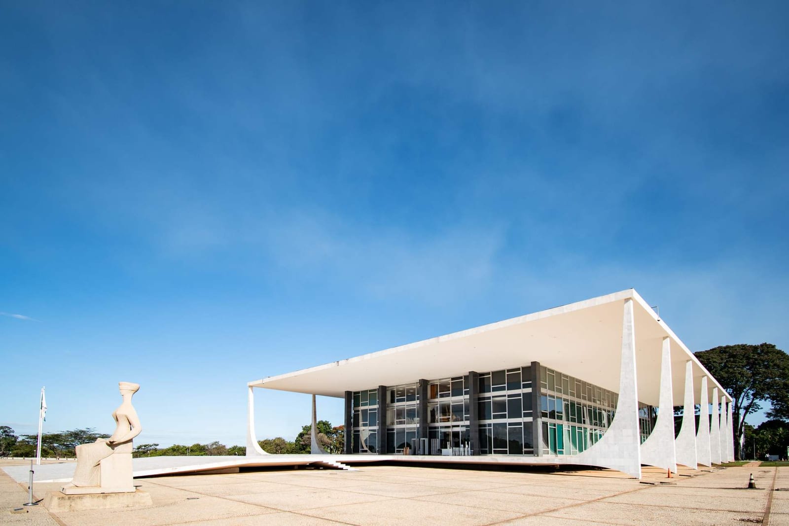 A modernist courthouse with a sweeping cantilevered colonnade beneath a clear blue sky