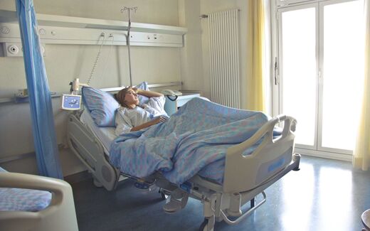 A patient in a hospital bed with an IV pole, a generic stand-in for the hospital infusion-therapy setting