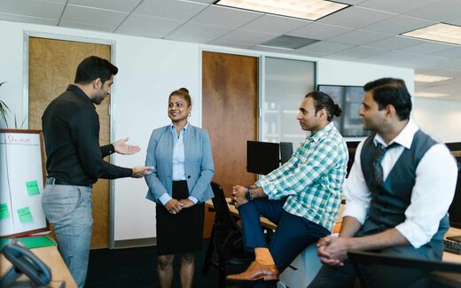A regulatory team briefing stands around a whiteboard in a bright office