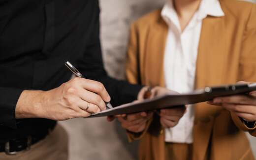 Close-up of hands signing an approval document on a clipboard, standing in for the FDA's nonprescription approval of Brytly