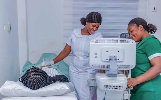 Two clinicians performing a cardiac ultrasound exam on a patient in a bright exam room