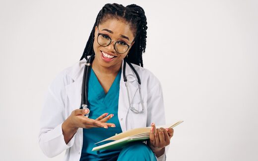 A physician in a white coat reviews a folder while smiling