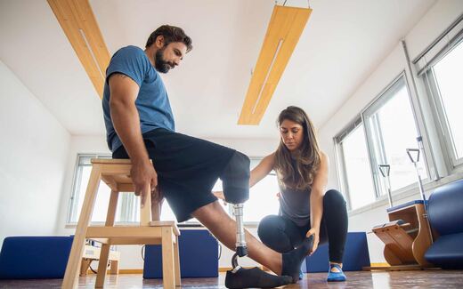 A physiotherapist in a bright studio helps a patient fit and adjust a prosthetic leg, a generic stand-in for orthopedic device care